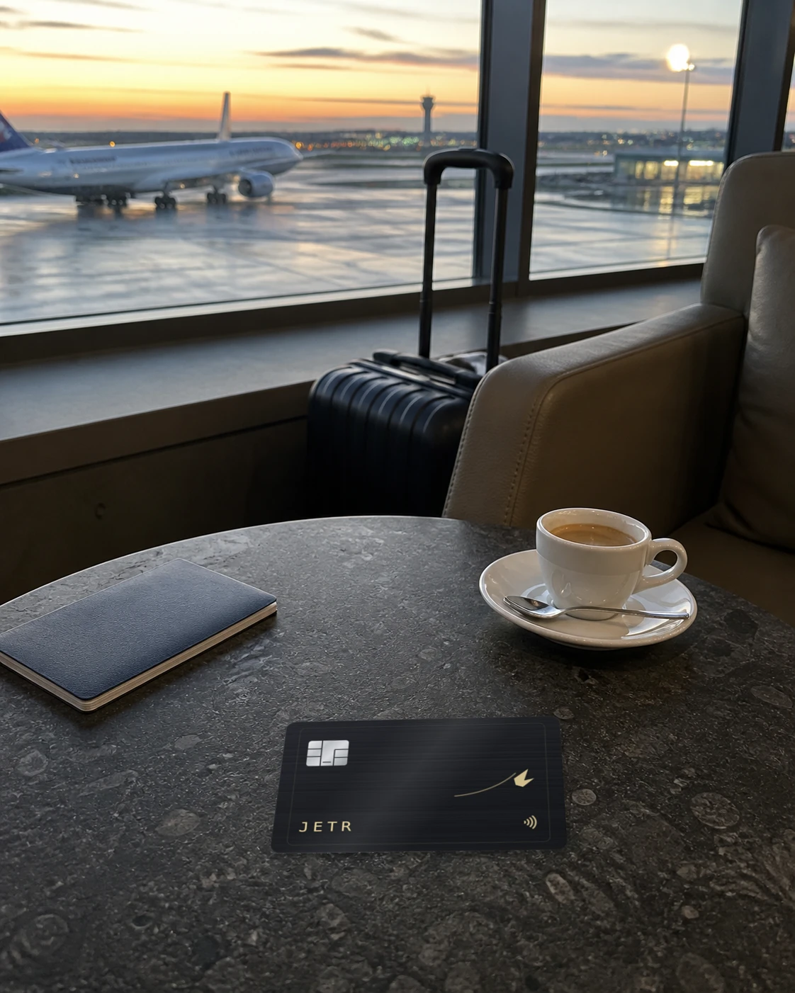 The JETR card on a lounge table with an espresso, an aircraft on the apron beyond.